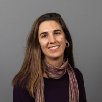 Brown haired woman with scarf in front of gray background