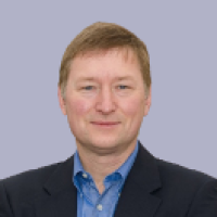 Man wearing blue shirt and blazer in front of light blue background