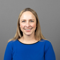Woman wearing bright blue shirt in front of gray background
